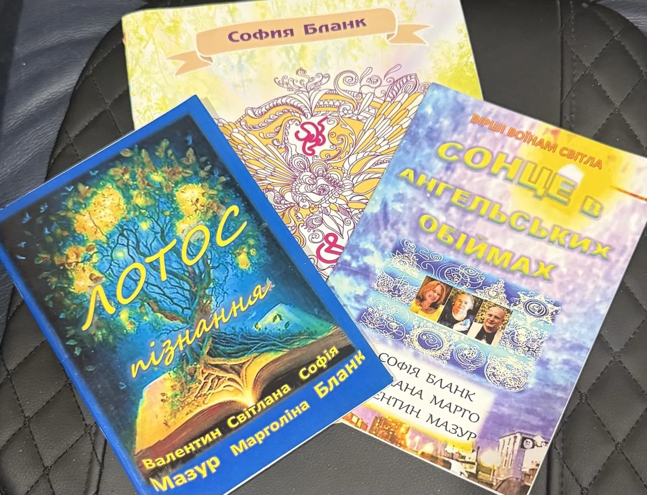 Три книги Софии Бланк с кириллическими названиями, лежащие на стеганой поверхности